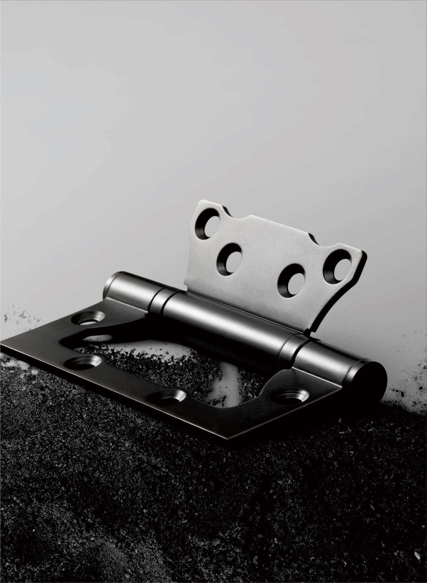 Metallic door hinge on a textured surface with a light gray background