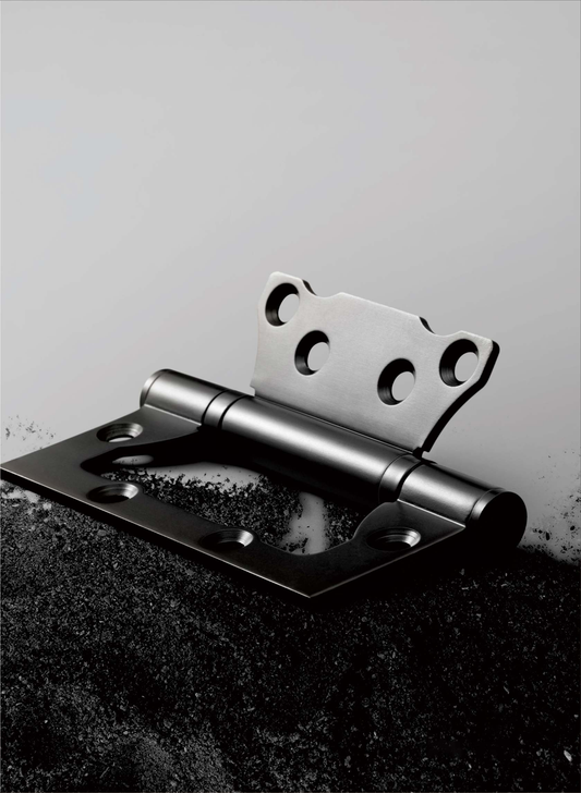 Metallic door hinge on a textured surface with a light gray background