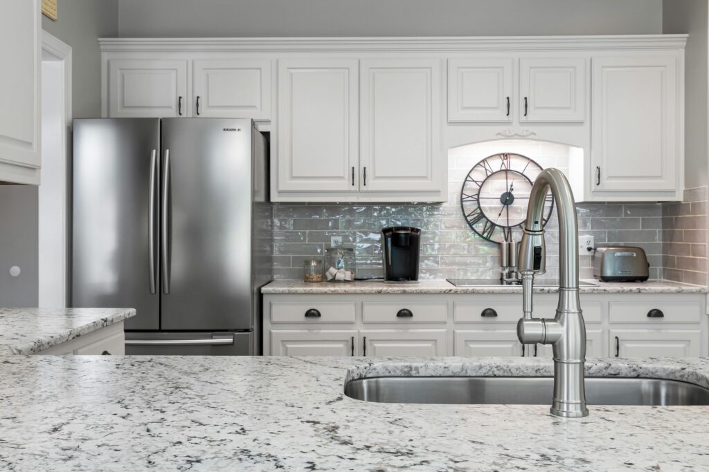 Elegant white kitchen featuring stainless steel appliances, granite countertops, and modern design elements.