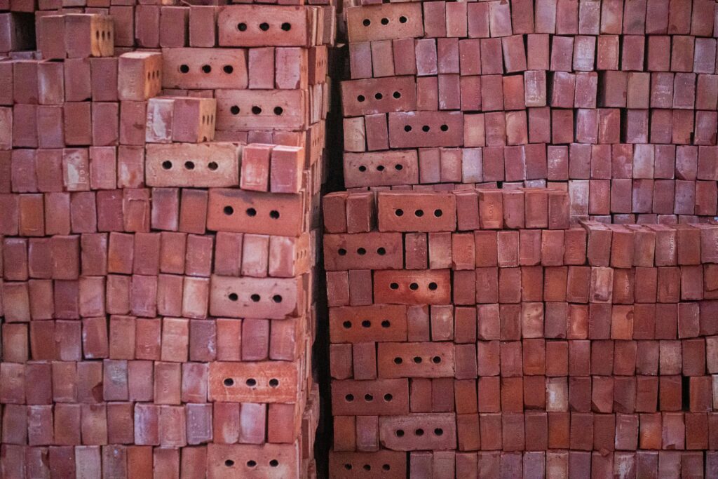 A detailed view of organized stacks of red bricks, creating a textured pattern outdoors.